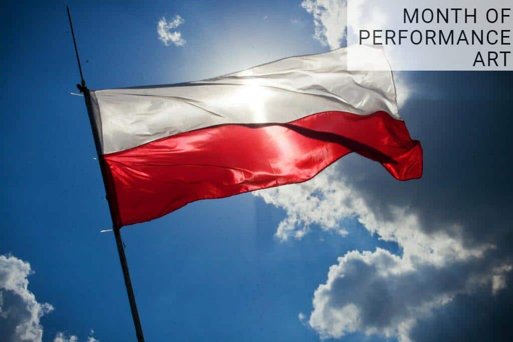 A Polish flag flutters against a bright blue sky with clouds, symbolizing national pride.